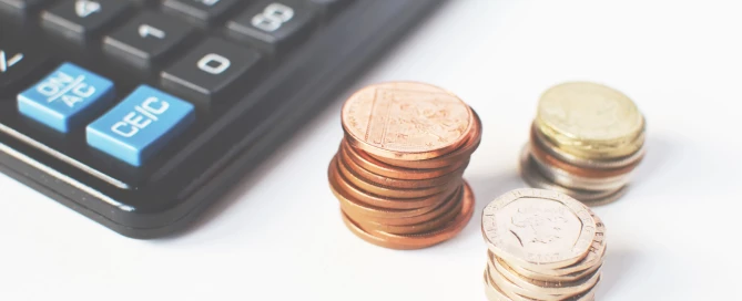 Gros plan sur des pièces de monnaie près d’une calculatrice pour illustrer la rémunération variable