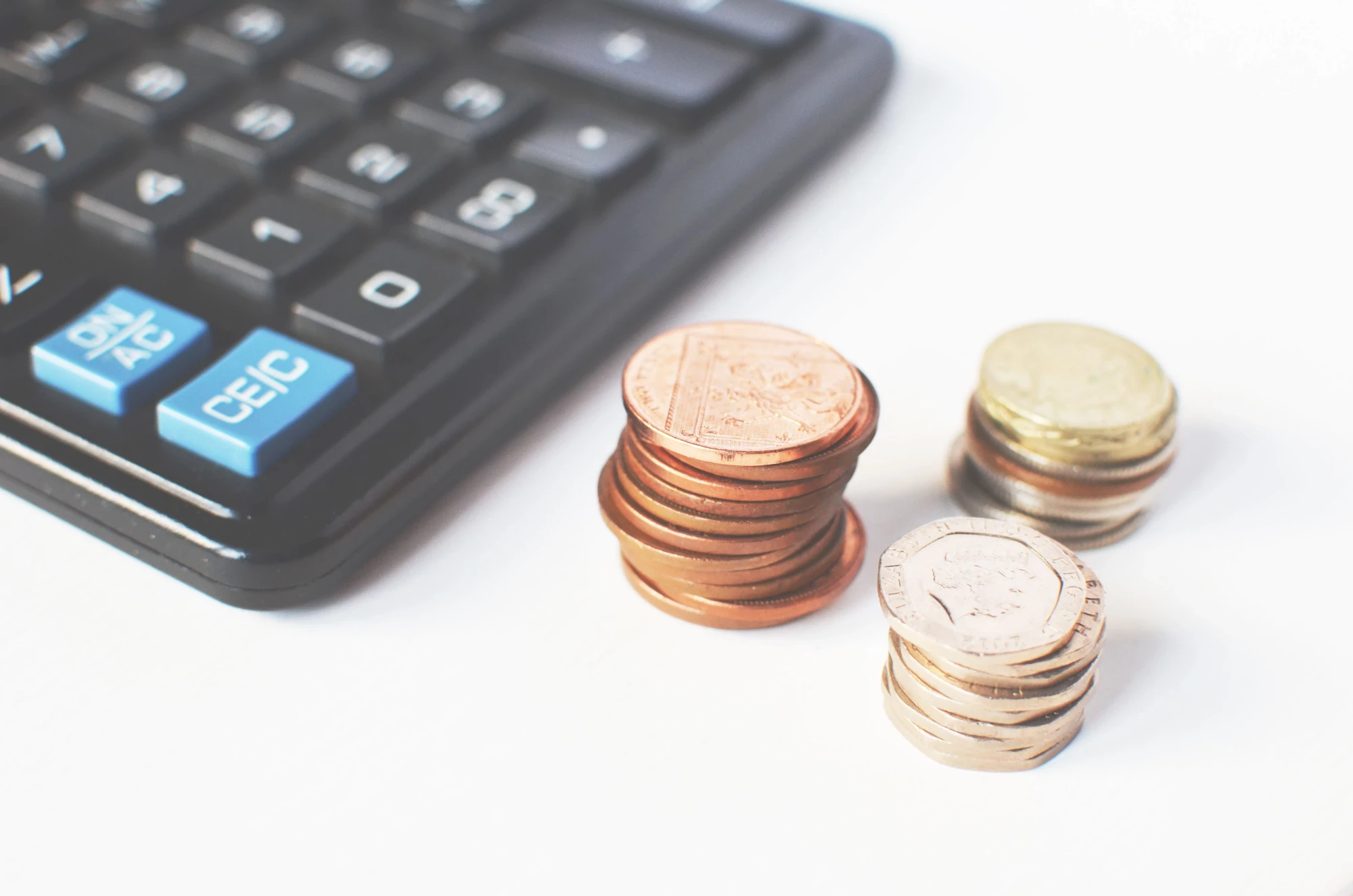 Gros plan sur des pièces de monnaie près d’une calculatrice pour illustrer la rémunération variable