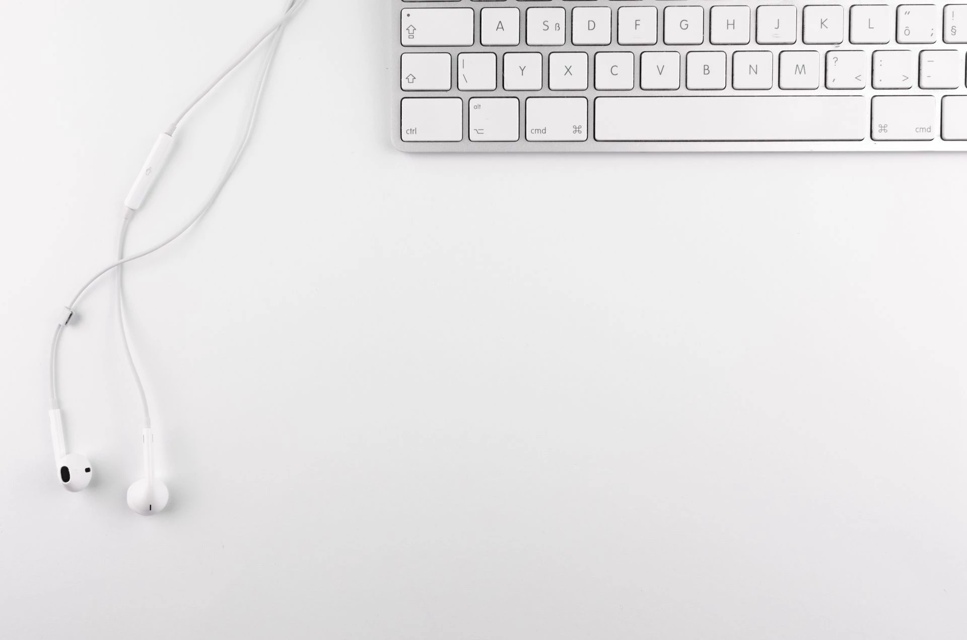 Clavier et écouteurs blancs sur un bureau lumineux pour illustrer le télétravail